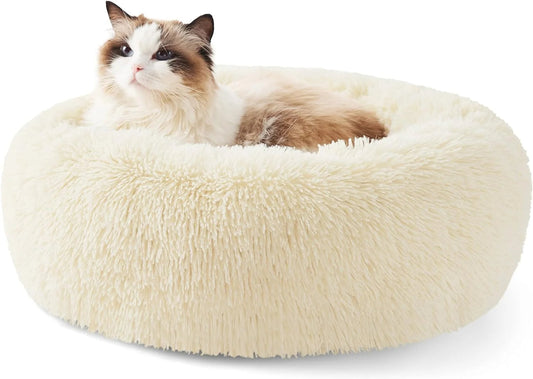 Cat lying on a fluffy beige pet bed against a white background