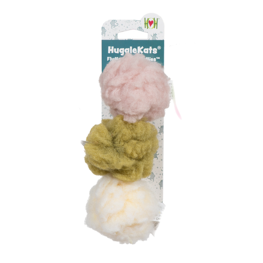 Three pom-poms in pink, yellow, and white on a HuggleMutt branded card against a white background.