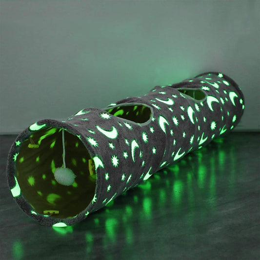 Glowing cat toy tunnel with star and moon pattern on a dark surface.