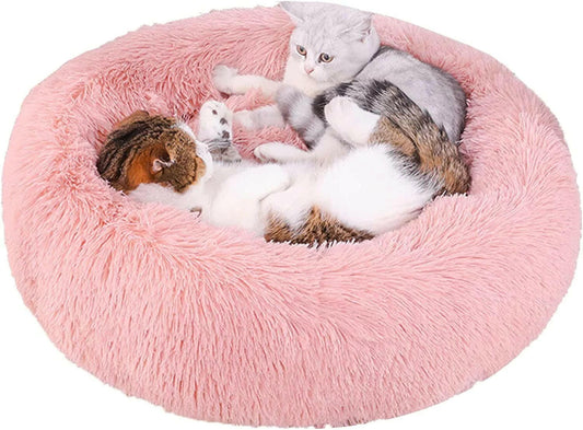 Pink fluffy pet bed with three cats inside on a white background