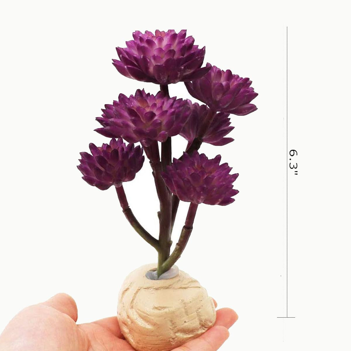 Small purple artificial flower arrangement in a decorative pot held by a hand on a white background.