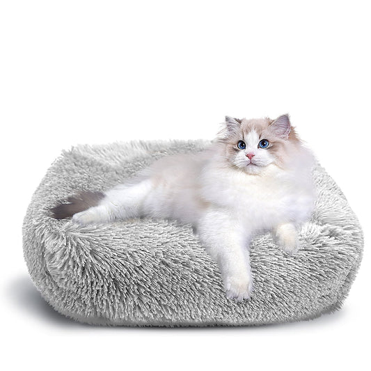 Cat lying on a fluffy gray pet bed against a white background
