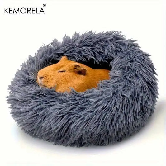 Gray fluffy pet bed with a small animal inside on a white background, featuring the brand 'KEMORELA'.
